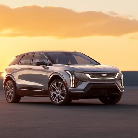 Cadillac Optiq electric vehicle viewed from the front passenger side under a sunset sky on an open rooftop