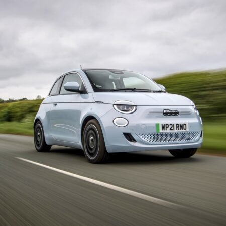 Fiat 500e electric vehicle in motion on a rural highway under cloudy skies